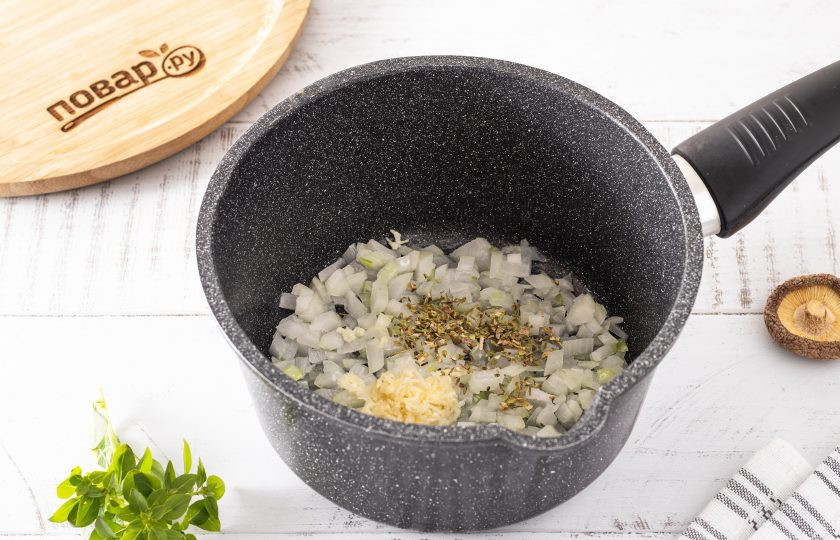 1. Этап. Грибной суп на кокосовом молоке: В кастрюле разогрейте оливковое масло. Обжарьте нарезанный кубиками репчатый лук с измельченным чесноком и сушеным орегано до мягкости и легкого золотистого цвета.