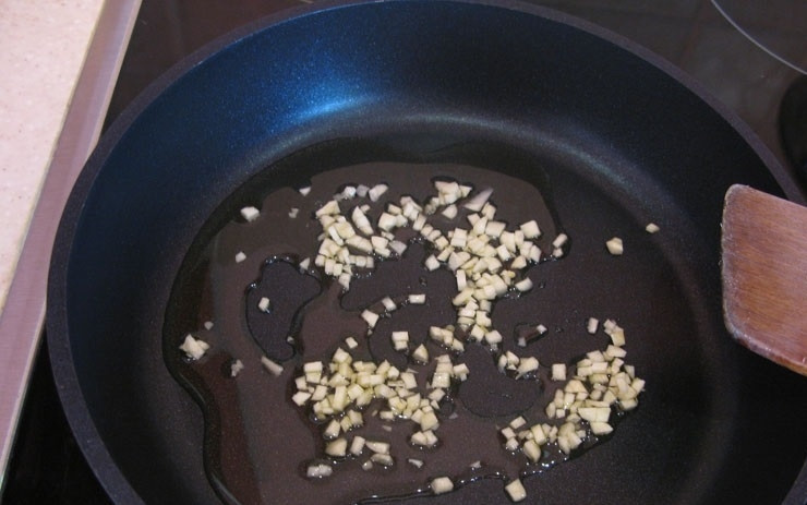 1. Этап. Китайская лапша с морепродуктами: 5. Сковороду ставлю на огонь, вливаю оливковое масло и разогреваю его, чищу чеснок и нарезаю его мелко, отправляю на разогретую сковороду.