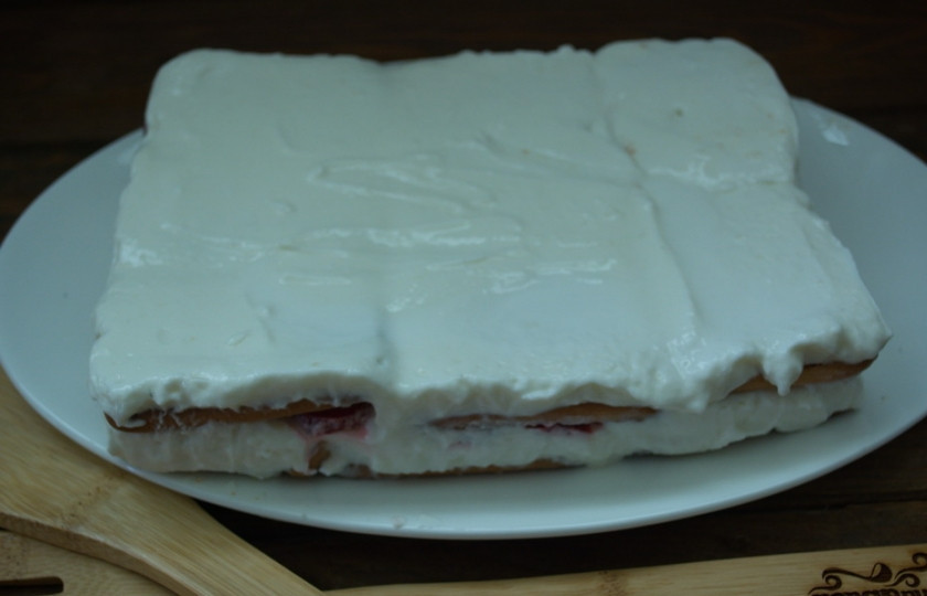 1. Этап. Клубнично-творожный торт без выпечки: Разровняйте. Поставьте форму с тортом в холодильник или в морозилку. В морозилке торт пробудет 30-40 минут, а в холодильнике до 2 часов. Спустя время извлеките торт из формы. Удалите пленку. Перенесите торт на блюдо.