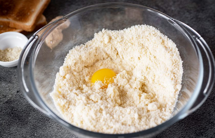 1. Этап. Пирог с патокой: Мучную крошку из чаши блендера выложите в миску, добавьте желток от одного яйца, соль, ледяную воду.