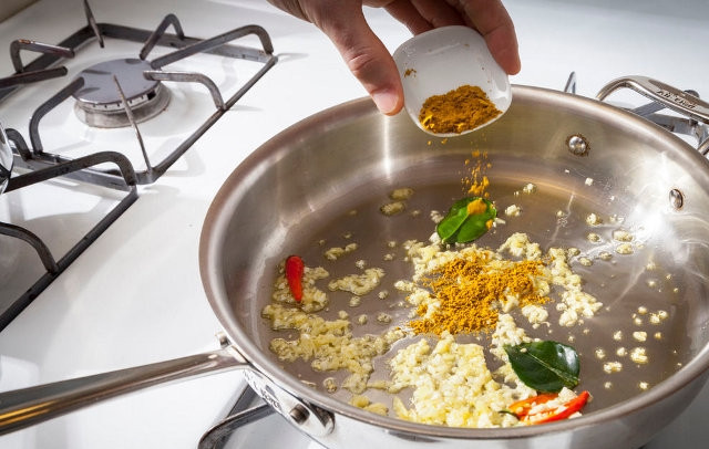 1. Этап. Треска, тушенная в молоке: В глубокой сковороде или кастрюльке разогрейте оливковое масло. Добавьте в него чеснок и имбирь, перчики чили и лимонный лист (или лавровый). Перемешайте, готовьте одну минуту. Потом постепенно всыпьте карри, постоянно помешивая при этом не переставая.