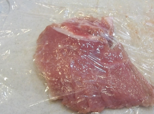 1. Этап. Французские отбивные из свинины в духовке: 9. Каждый кусочек мяса оборачиваю в пищевую пленку и отбиваю молоточком.