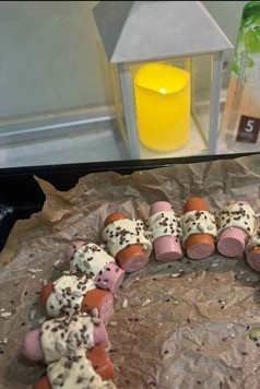 1. Этап. Универсальный веночек: На противень, застеленный пергаментом, плотно друг к другу выложить сосиски в тесте в форме веночка. Сверху смазать желтком и посыпать кунжутом. Отправить выпекаться в духовку при 180 градусов на 20-25 минут.