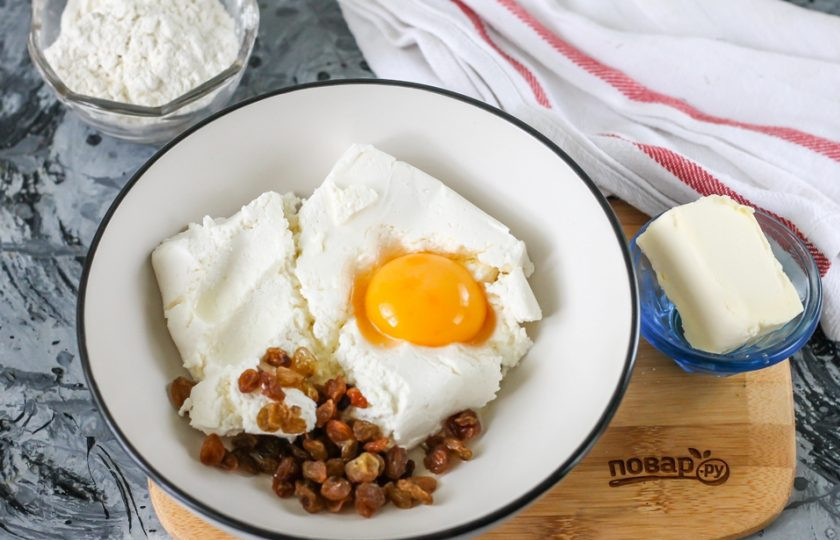 1. Этап. Сырники из кислого творога: Творог любой жирности выложите в миску или глубокую тарелку, всыпьте туда же соль, вбейте куриное яйцо. Добавьте изюм. Предварительно его можно запарить в кипятке за час до приготовления сырников.