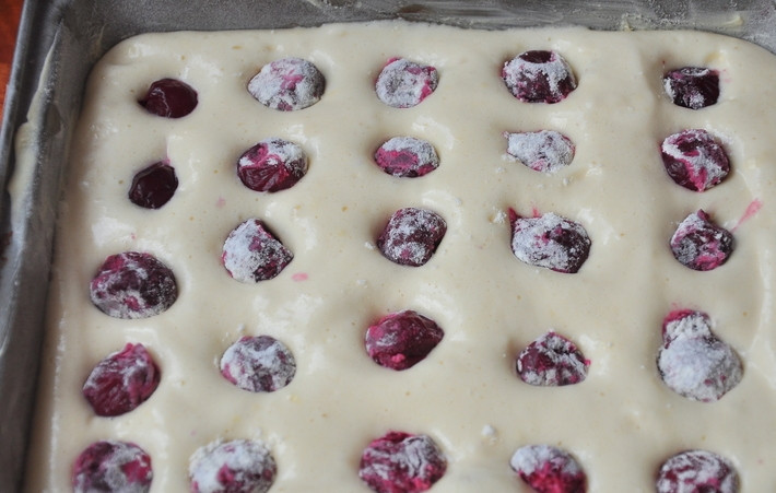 1. Этап. Бисквитный пирог: 6. Жаропрочную форму смажьте немного маслом и присыпьте мукой. Выложите тесто и разровняйте. Ягоды (в этот простой рецепт бисквитного пирога используется вишня) обваляйте в крахмале и распределите по поверхности.