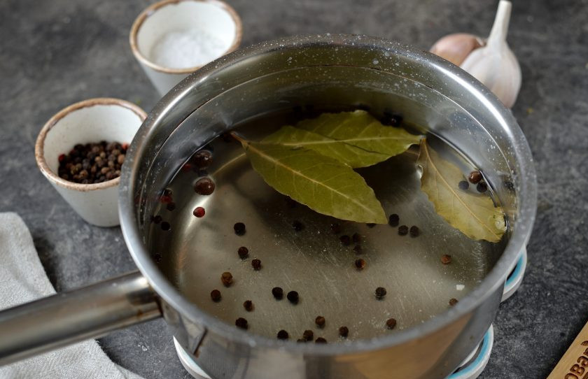1. Этап. Сало соленое в рассоле по-деревенски: Вскипятите в сотейнике воду, всыпьте перцы, лавровый лист и соль. Доведите до кипения, растворите все кристаллы соли, помешивая рассол ложкой.