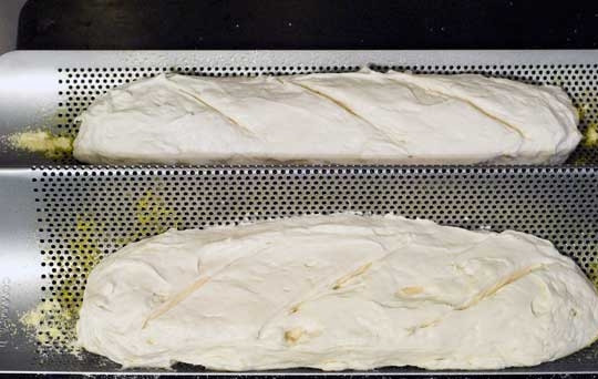 1. Этап. Французский багет в духовке: Сформируйте из теста 2-3 багета, сделав борозды сверху. Уложите их на форму.