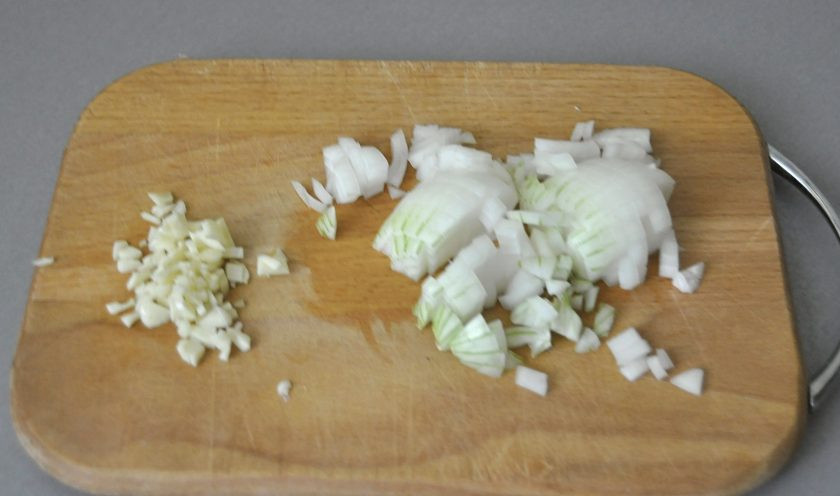 1. Этап. Греческая закуска Мелидзана: Пока запекаются овощи, займитесь начинкой, измельчите лук и чеснок.