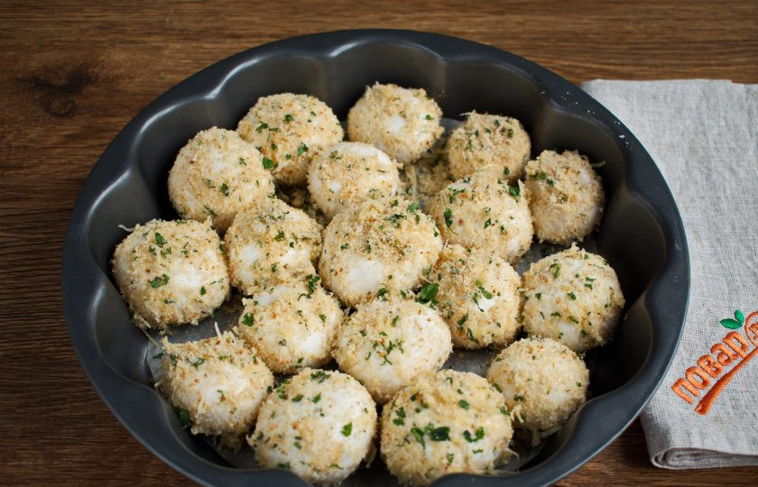 1. Этап. Шампиньоны в чесночной панировке: Окуните шампиньоны в белок, обваляйте в панировке, разложите на подготовленную форму. Запекайте в разогретой духовке в течение 15 минут.