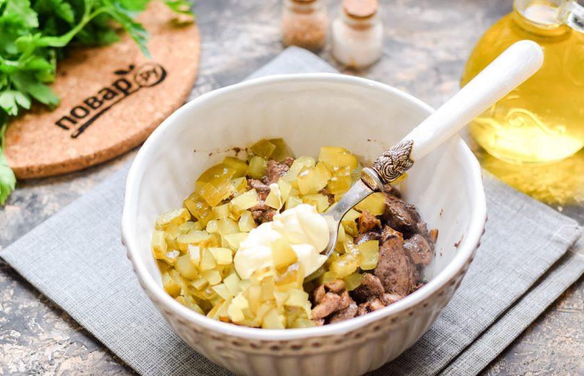 1. Этап. Салат Подснежник с печенью: Переложите печень и грибы в тарелку, добавьте мелко нарезанные соленые огурцы, майонез, соль и перец. Перемешайте все.