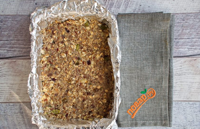 1. Этап. Энергетические батончики: Форму для запекания застелите фольгой, формируя бортики. Выложите готовую массу, хорошо утрамбуйте. Поставьте запекаться в духовку на 15 минут при 180 градусах.