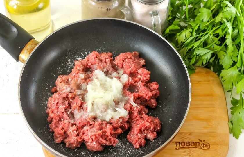 1. Этап. Бадымджан: Очистите и промойте лук от кожуры, натрите его на терке с мелкими ячейками в фарш. Всыпьте соль и молотый черный перец, перемешайте фарш и выложите его в сковороду с растительным маслом. Обжарьте в течение 5-7 минут до румяности.