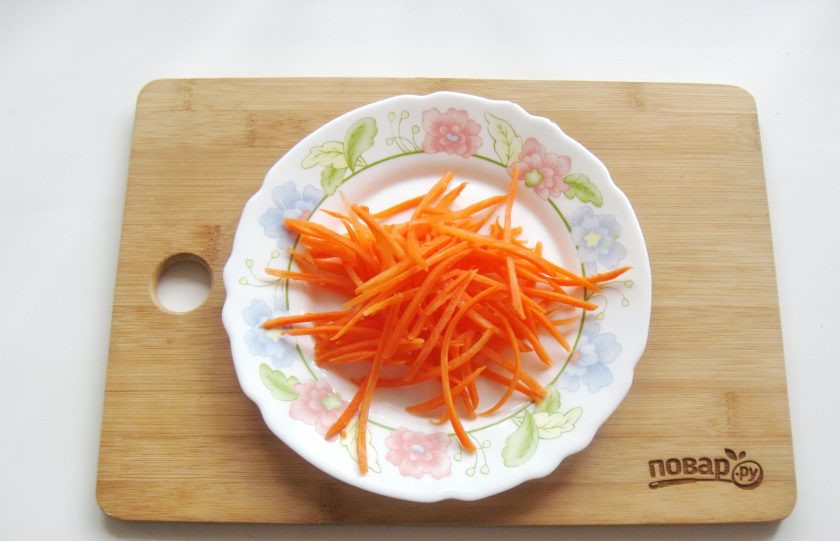 1. Этап. Огурцы по-корейски на зиму без стерилизации: Морковь очистите, помойте и натрите на терке для моркови по-корейски или нарежьте тонкой соломкой.