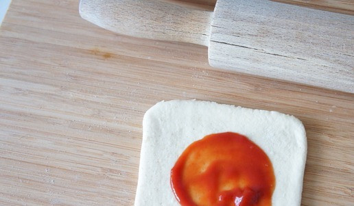 1. Этап. Мини-пиццы Тыквы: Каждый квадрат теста слегка раскатать. Смазать томатным соусом или кетчупом.