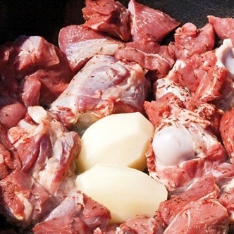 1. Этап. Казан-кебаб: Берем казан, на дно выкладываем две очищенных сырых картофелины (это делается для того, чтобы мясо не купалось в собственном жире и не тушилось). Далее укладываем в казан, слегка смазанный маслом, наше мясо.