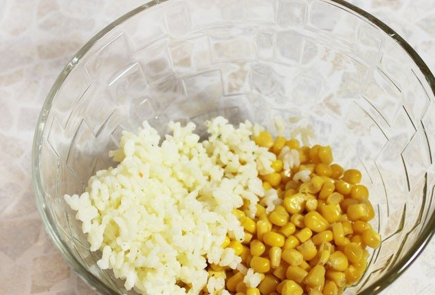 1. Этап. Салат с крабовыми палочками и рисом: 2. Отвариваем рис в слегка подсоленной воде, после чего откидываем его на сито, чтобы стекла влага, после этого перекидываем рис в миску. Открываем банку консервированной кукурузы, сливаем с неё жидкость, высыпаем кукурузу в миску к рису.