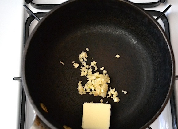 1. Этап. Пицца со сливочным соусом: 6. В другую сковороду добавьте сливочное масло, почистите и выдавите с помощью чеснокодавки 1 зубчик чеснока.