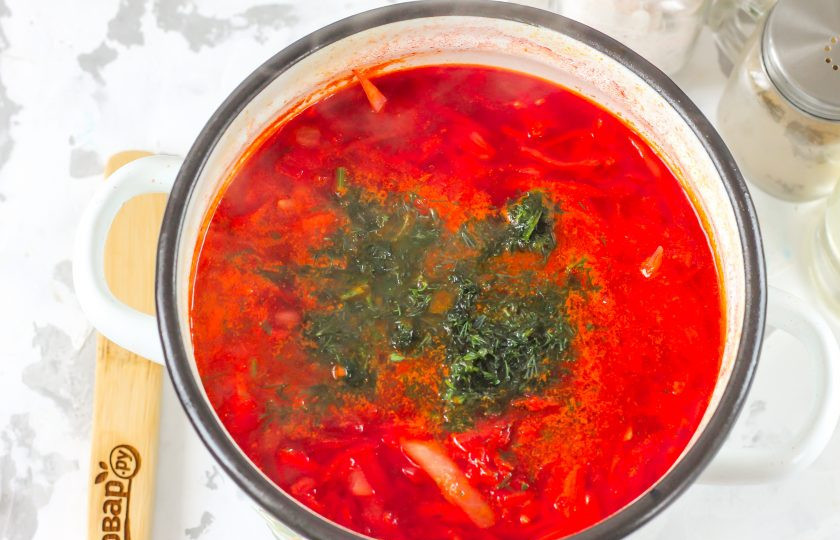 1. Этап. Борщ по ГОСТу: Последними выложите в емкость промытую, а затем измельченную зелень укропа или петрушки, спрессованный зубчик чеснока, предварительно очищенный. Томите блюдо на умеренном нагреве примерно 1-2 минуты.