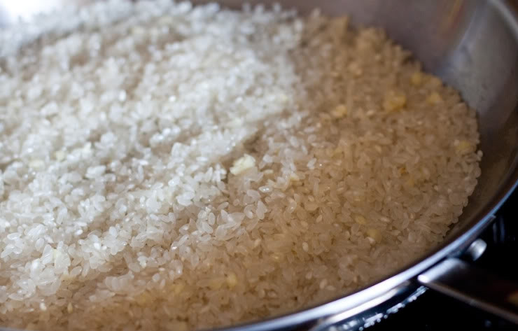 1. Этап. Рис по-мексикански: Разогрейте на среднем огне сковороду и растопите на ней масло. Всыпьте рис и выдавите в него чеснок. Всё перемешайте. Жарьте рис около 10 минут, часто помешивая. Пока рис жарится, смешайте в миске томатный соус, куриный бульон, соль и перец.