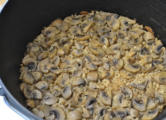 1. Этап. Перловка с шампиньонами: 5. Добавьте перловую крупу, посолите и перемешайте. Накройте казан крышкой и отправьте в разогретый до 175 градусов духовой шкаф на 1 час.