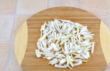 1. Этап. Куриный салат с ветчиной и опятами: Лук очистите от шелухи, вымойте и нарежьте тонкими дольками. Лучше выбирать не очень горький лук, белый салатный, к примеру.