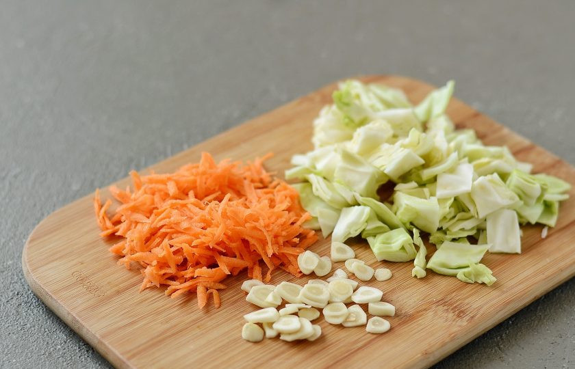 1. Этап. Маринованная капуста без уксуса: Капусту нарежьте небольшими квадратиками, чеснок пластинами, а морковь натрите на крупной терке.