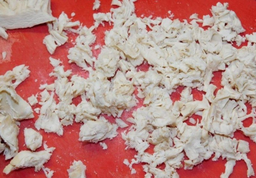 1. Этап. Слоеный салат с курицей, грибами и грецкими орехами: Куриное филе отварите, остудите и мелко нарежьте. Выложите вторым слоем салата и смажьте майонезом.