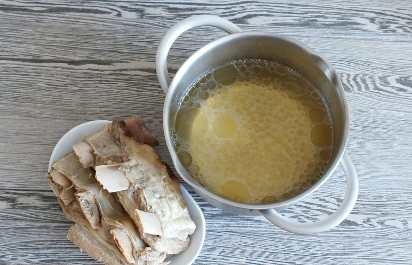 1. Этап. Солянка на говяжьем бульоне: Сварите из говяжьих ребрышек бульон. Оставьте мясо охлаждаться в бульоне. После достаньте его. Бульон слегка подогрейте и процедите.