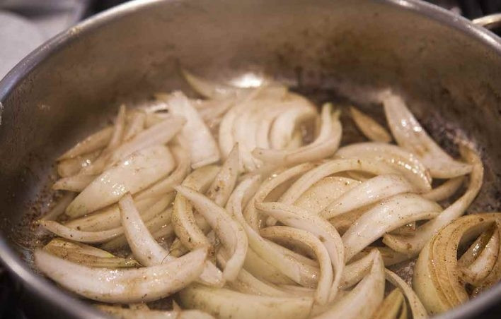 1. Этап. Куриные окорока с соусом: 4. Верните сковороду на огонь и разогрейте ее, нарежьте лук клиньями и выложите в сковороду, обжаривайте около 5-8 минут.