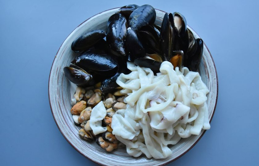 1. Этап. Суп Том ям с мидиями: Подготовьте морепродукты. Кальмары освободите от хорды, шкурки и внутренностей. Нарежьте филе кольцами. Мидии хорошо промойте. Особое внимание уделите мидиям в раковинах. Удалите с раковин наросты, тину (если имеется). Промойте под проточной водой, с целью удаления песка.