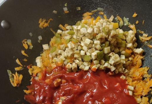 1. Этап. Жареная капуста с баклажанами и перцем: Выкладываем к луку с морковью наши баклажаны с перцем и сразу добавляем томатный соус.