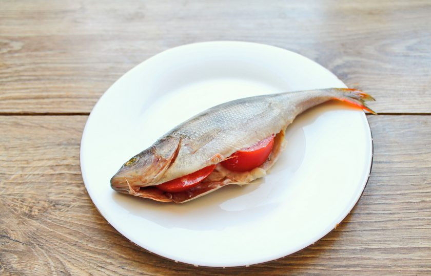 1. Этап. Окунь в духовке с чешуей: Репчатый лук мелко порежьте и смешайте с майонезом, помидор порежьте на дольки. Окуней посолите, поперчите и выложите в брюшко лук с майонезом, вставьте ломтики помидоров.