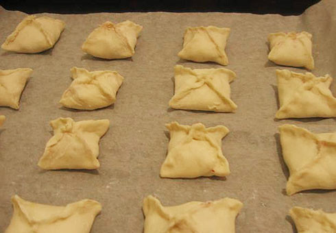 1. Этап. Малиновые пирожки: 5. На тесто выложить ягоды и аккуратно завернуть. Можно сделать не только квадратные пирожки, но и треугольнички. Также при желании можно сделать небольшие надрезы сверху. Отправить противень в разогретую духовку и выпекать до золотистого цвета.