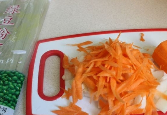 1. Этап. Салат с кальмарами и шампиньонами: 1. Первым делом очистите лук и нарежьте небольшими кубиками. Морковь очистите и натрите на терке. На сковороде разогрейте растительное масло.