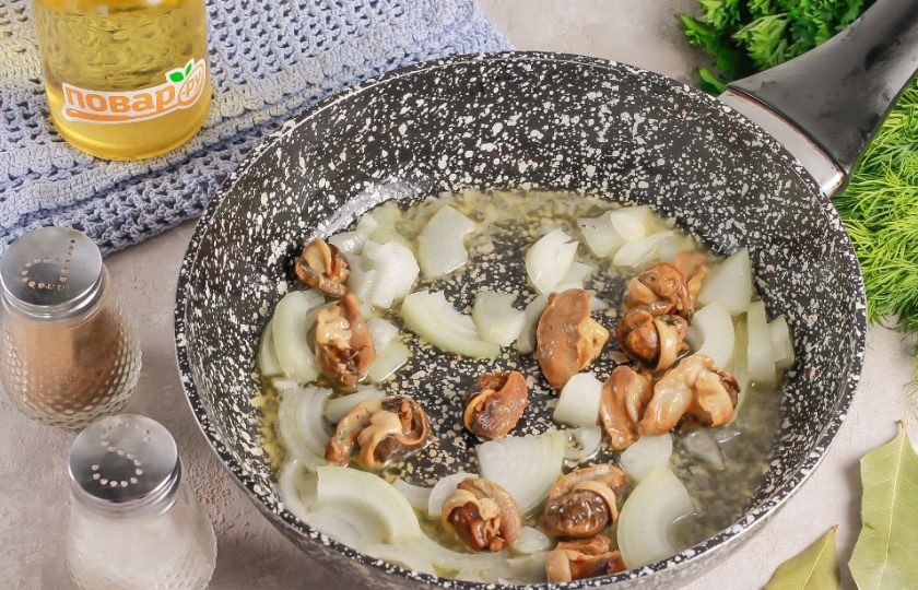 1. Этап. Суп из виноградных улиток: Сливочное масло растопите в сковороде. Нарежьте репчатый лук полукольцами и добавьте в сковороду вместе с улитками. Улитки приобретайте маринованные или вареные. Обжарьте все примерно 3-4 минуты до румяности лука.