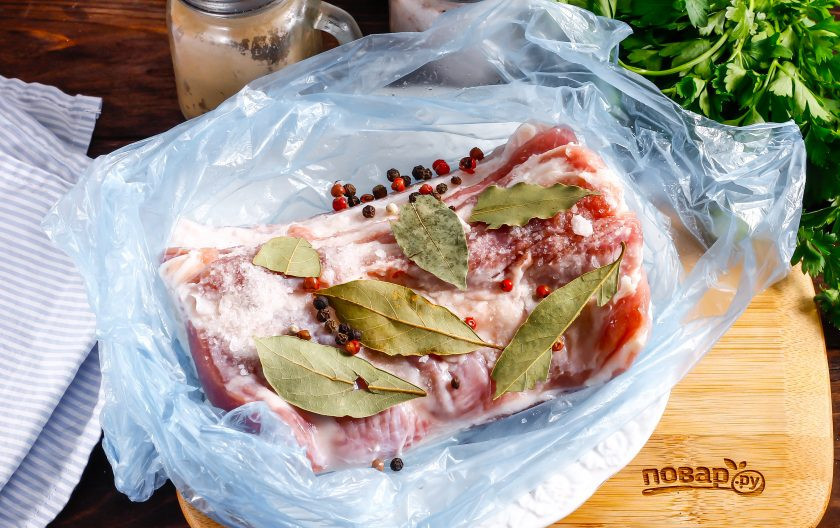 1. Этап. Свиная брюшина вареная в пакете: Поместите мясо в целлофановый пакет, присыпьте солью, горошинами черного перца и выложите лавровые листья. По желанию можете использовать и другие пряности, специи.