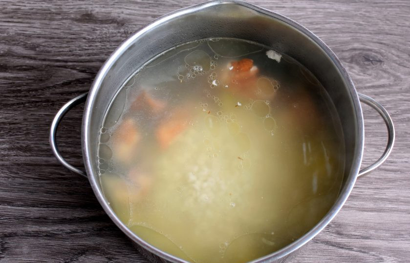 1. Этап. Рассольник с копченостями: Копченые куриные спинки, как и любое копченое мясо на кости, я нарезаю на кусочки и сначала заливаю небольшим количеством воды. Даю закипеть. Затем сливаю воду и заливаю копчености свежей водой уже для супа. Довожу до кипения и варю в зависимости от вида мяса. Для курицы достаточно потомиться на слабом огне после повторного закипания 10 минут. В кипящий бульон добавьте картошку и варите до полуготовности. Затем добавьте крупу. Регулируйте густоту супа по своему вкусу.