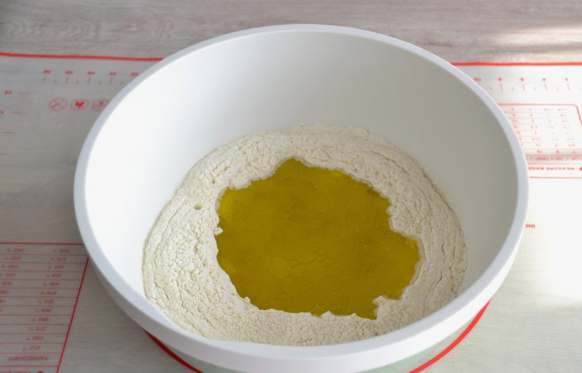 1. Этап. Итальянский хлеб с розмарином в духовке: Сделайте в муке углубление, влейте теплую воду и 80 грамм оливкового масла. Соль добавлять не надо.