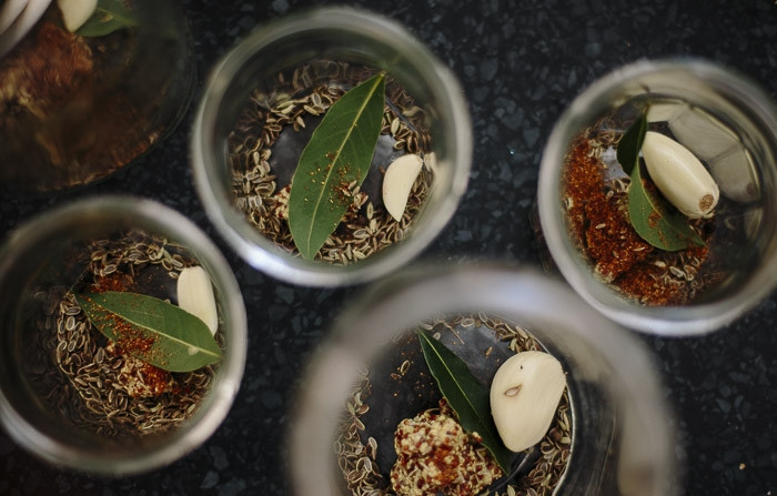 1. Этап. Огурчики по-польски: На дно банок выложите по головке чеснока, семена укропа, специи, лавровый лист. Затем плотно утрамбуйте огурцами.