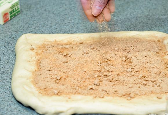 1. Этап. Хлеб с корицей: 6. Раскатать тесто в прямоугольник 30Х45 см. Смазать тесто молоком, оставляя границу по краю 2,5 см. Посыпать тесто сахарной начинкой.