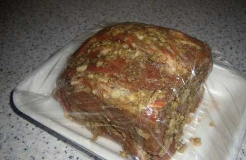 1. Этап. Запеченная шейка в фольге: Далее мы натираем мясо со всех сторон перцем и солью, а также пропущенным через пресс чесноком. Выкладываем шейку в лоток, заворачиваем ее в пищевую пленку и оставляем мариноваться на три часа при комнатной температуре.