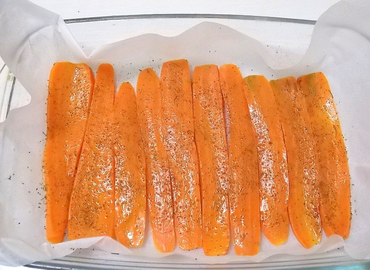 1. Этап. Паренки из моркови в духовке: Застелите противень бумагой для выпечки и уложите морковь в один слой. Смажьте ее малом и посыпьте специями.