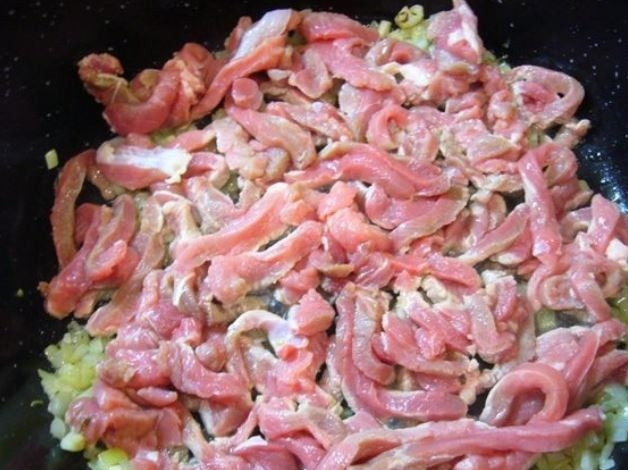 1. Этап. Телячье филе в томатном соусе: На сковороде с оливковым маслом обжарьте лук и чеснок до прозрачности. Затем отправьте в сковороду нарезанное брусочками филе.