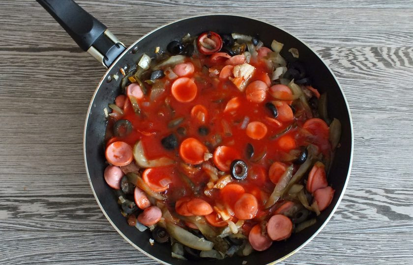 1. Этап. Солянка на говяжьем бульоне: Влейте томатную пасту в обжаренные овощи с сосисками. Доведите до кипения, перемешайте и снимите с огня.