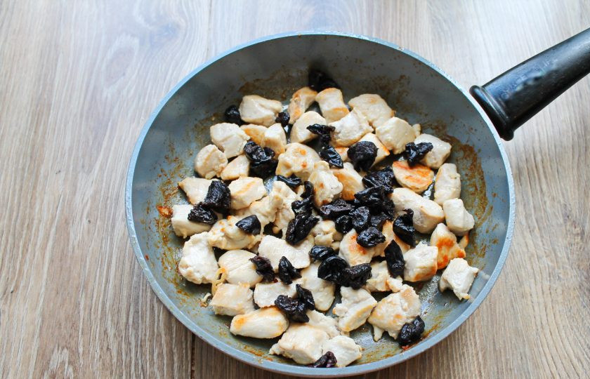 1. Этап. Куриное филе с черносливом: Подготовленный чернослив разрежьте на четыре части и добавьте в сковороду с куриным филе.