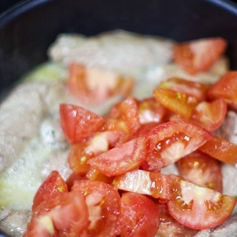 1. Этап. Рулетики из телятины: Помидоры бланшируйте (опустите в кипяток на 1 минуту и очистите от кожуры), нарежьте на небольшие кусочки и добавьте в сковороду.