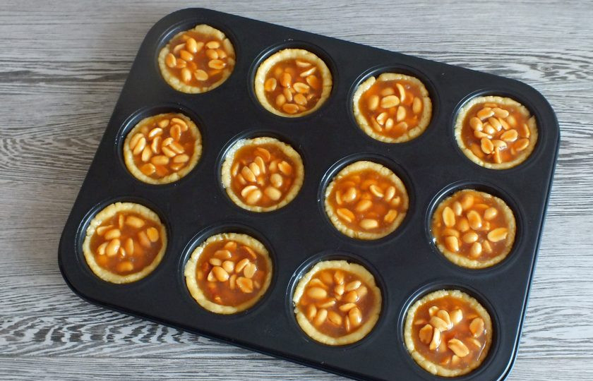 1. Этап. Тарталетки с орехами и карамелью: Выложите начинку. Поставьте в разогретую до 170 градусов духовку на 20-25 минут.