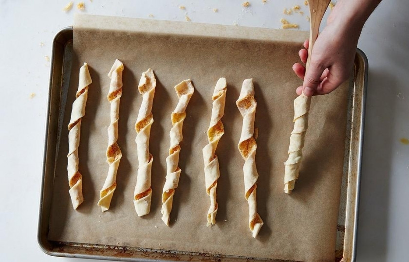 1. Этап. Сырные палочки из слоеного теста: Шаг 8. Аккуратно прокрутите каждую полосочку для получения спиральной формы, придерживая её верх и низ. Оставьте палочки на 20 минут, убедитесь, что они держат форму.