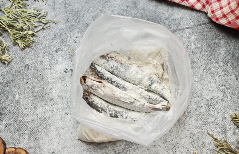 1. Этап. Жареная корюшка Питерская весна: В полиэтиленовый пакет всыпьте пшеничную муку, добавьте соль, черный перец и перемешайте. Выложите в пакет подготовленную корюшку, завяжите пакет и потрясите, чтобы корюшка покрылась мукой.