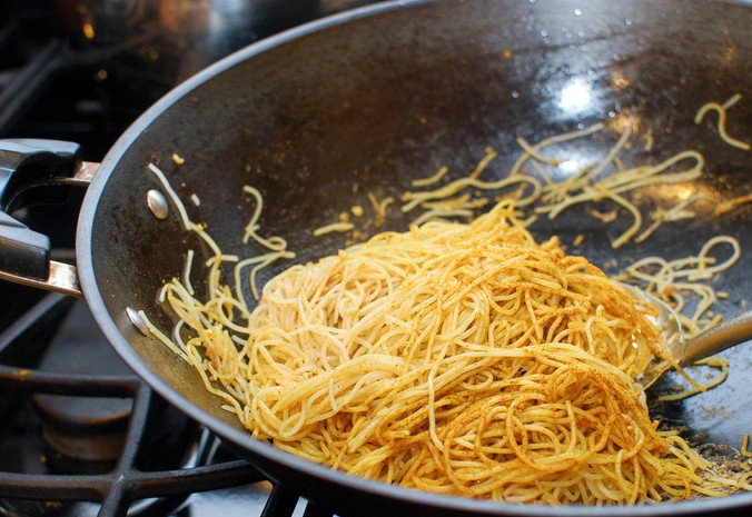 1. Этап. Лапша по-сингапурски: Проводим очистку вока. Разогреваем в нем еще масло и выкладываем лапшу. Обжариваем 30 секунд и добавляем соевый соус, измельченный чеснок и рисовое вино с белым перцем.